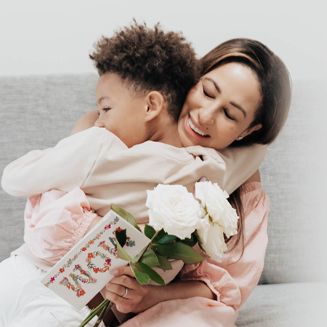 Son giving mom a hug, flowers and Papyrus Mother's Day Cards