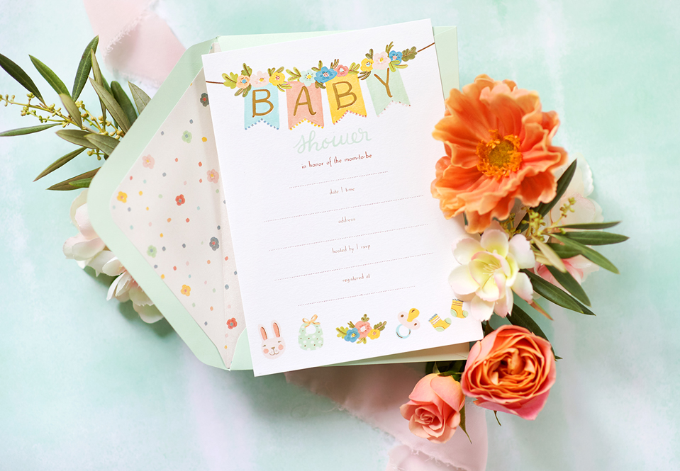 Baby invitation on a table with flowers