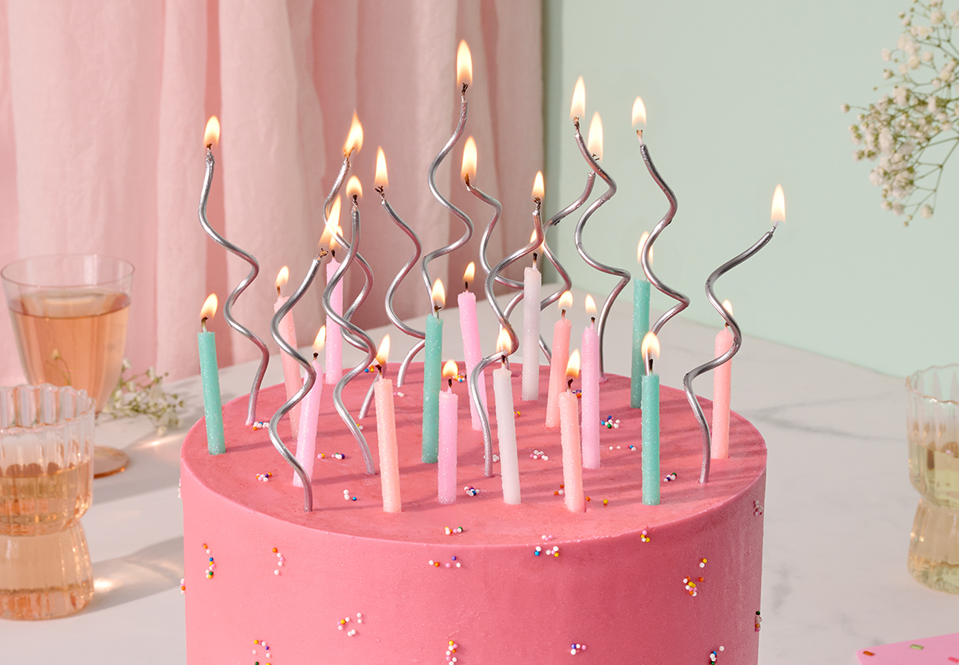 Pink cake with swirl and traditional candles.