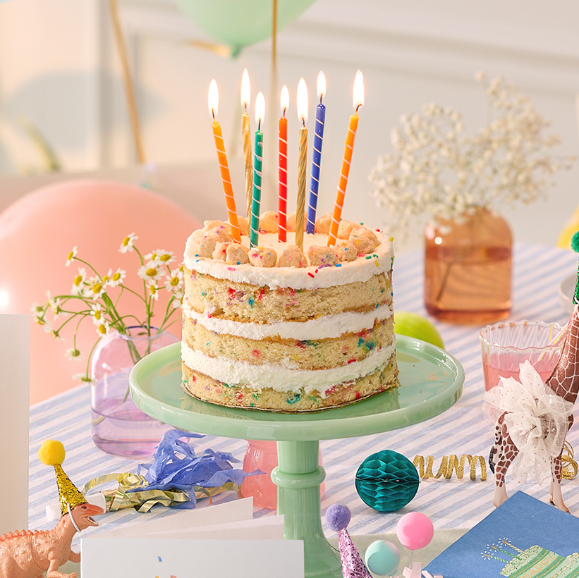 Milk Bar cake with colorful tall candles on a table during a celebration