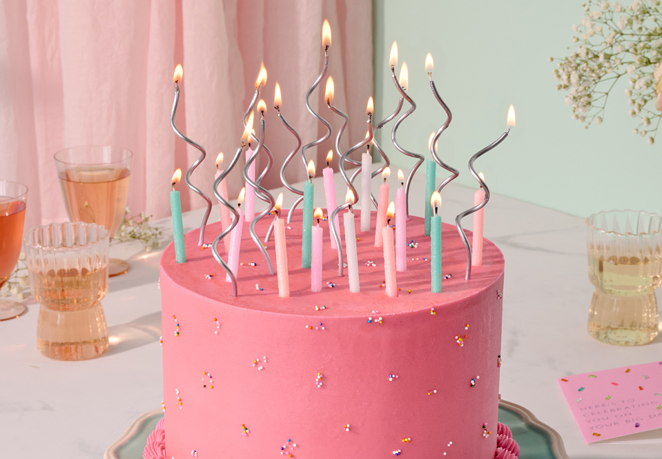 Pink birthday cake with traditional and swirl candles
