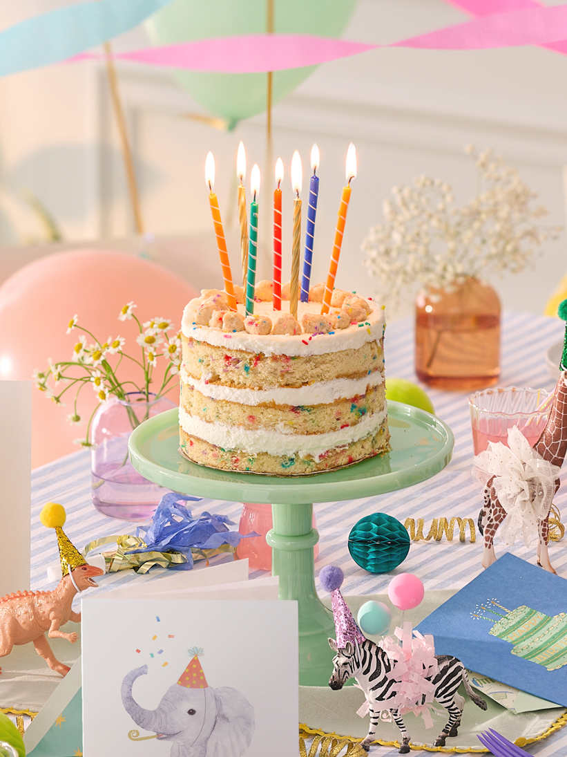 Milk Bar cake with colorful tall candles on a table during a celebration