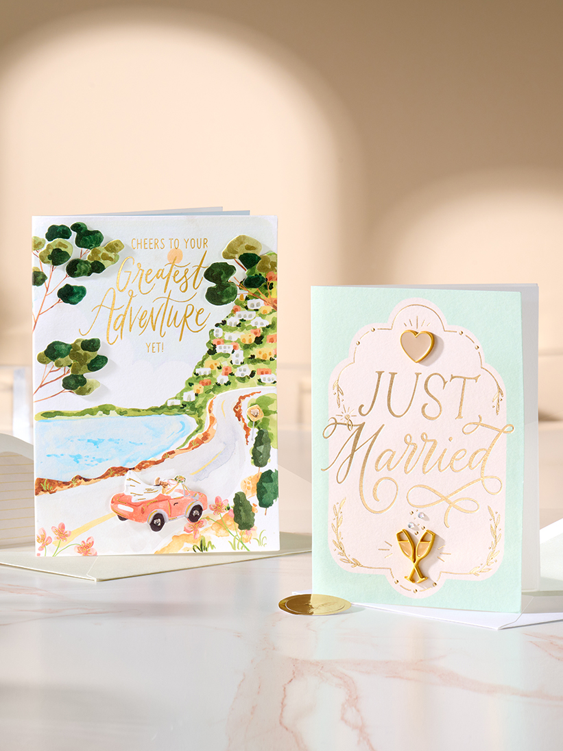 2 Wedding cards standing up on a table.
