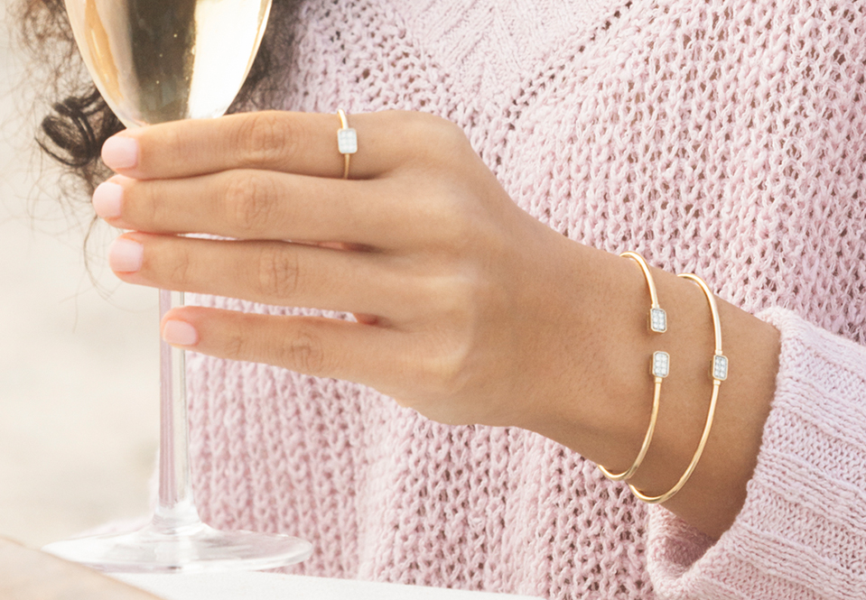 Hand with jewelry holding a champagne glass.