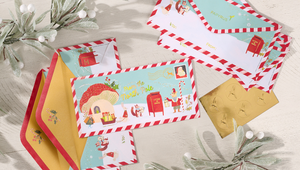 Envelopes arranged on a table with holiday greenery