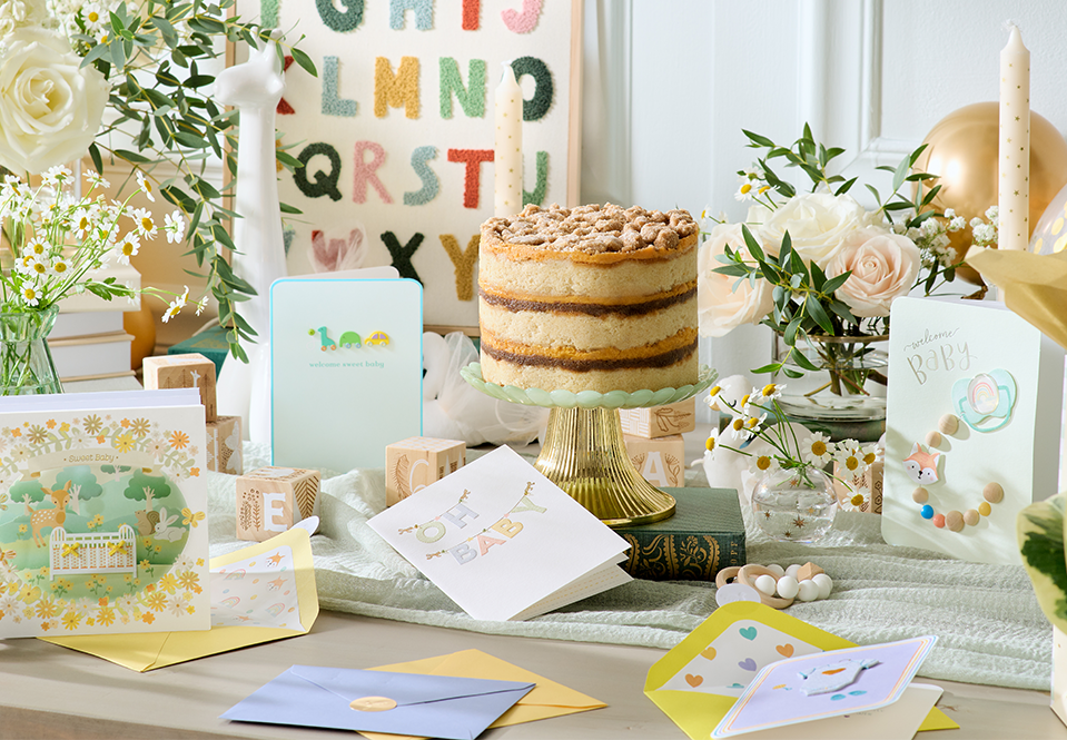 Baby cards on a table with a cake at a baby shower.