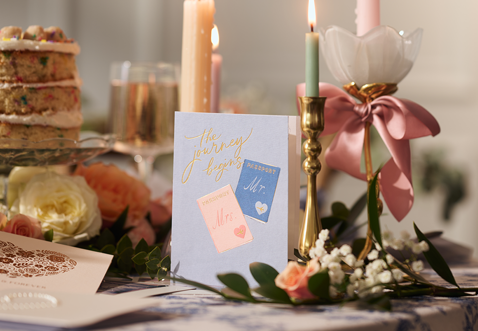 The Journey Begins Wedding card on a table with candles
