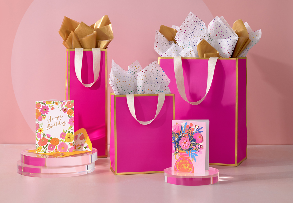 Pink gift bags and floral cards on a pink background