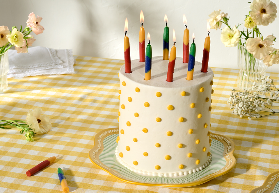 Multicolored candles on a white and yellow polka dot cake