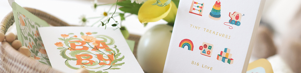Baby cards on a table with flowers and a basket